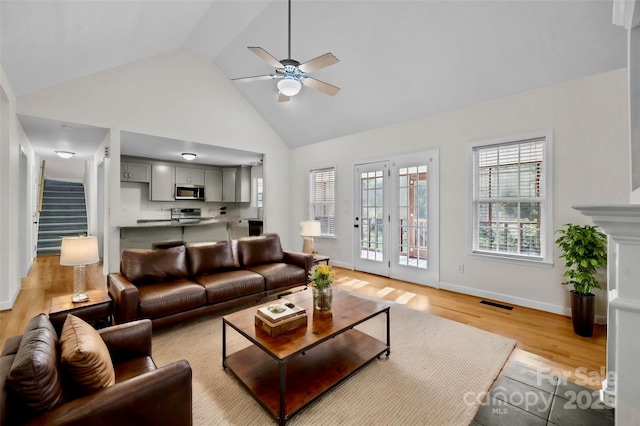 living room featuring light hardwood / wood-style flooring, high vaulted ceiling, and ceiling fan