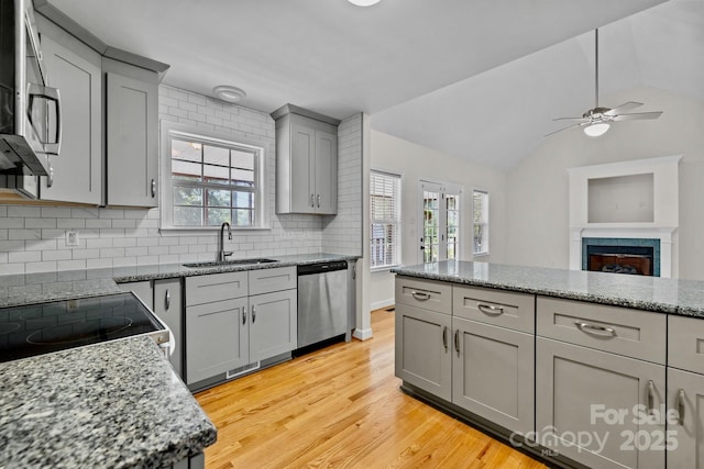 kitchen with sink, gray cabinets, stainless steel appliances, light stone counters, and light wood-type flooring