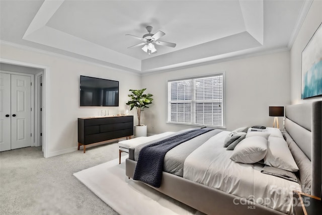 carpeted bedroom featuring a raised ceiling, crown molding, and ceiling fan