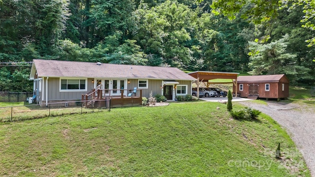 ranch-style home featuring a front lawn, a carport, and a storage unit