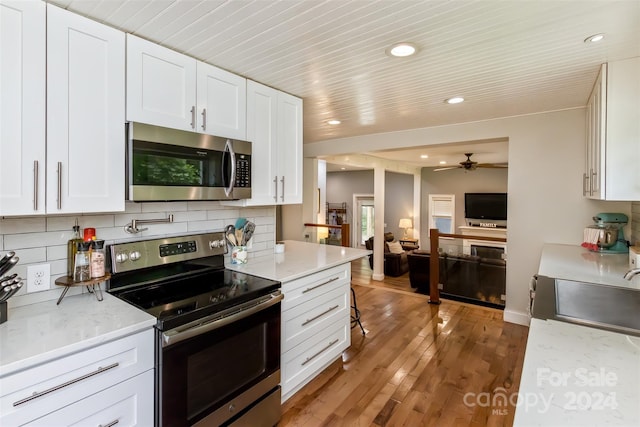 kitchen featuring light hardwood / wood-style flooring, decorative backsplash, stainless steel appliances, and white cabinetry