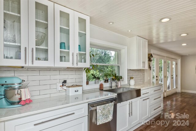 kitchen with dark hardwood / wood-style floors, plenty of natural light, stainless steel dishwasher, and backsplash