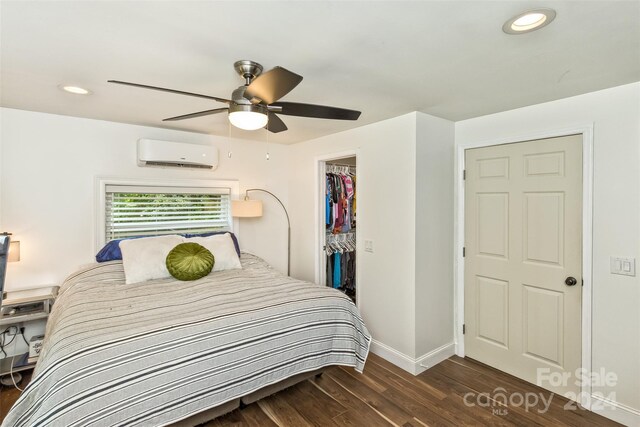 bedroom featuring ceiling fan, an AC wall unit, hardwood / wood-style flooring, a walk in closet, and a closet