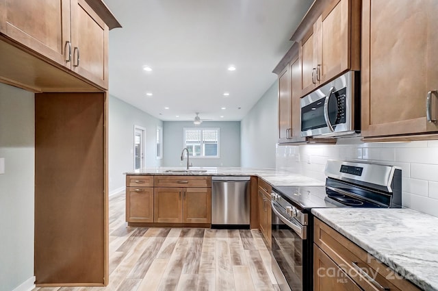 kitchen with kitchen peninsula, sink, light wood-type flooring, tasteful backsplash, and stainless steel appliances