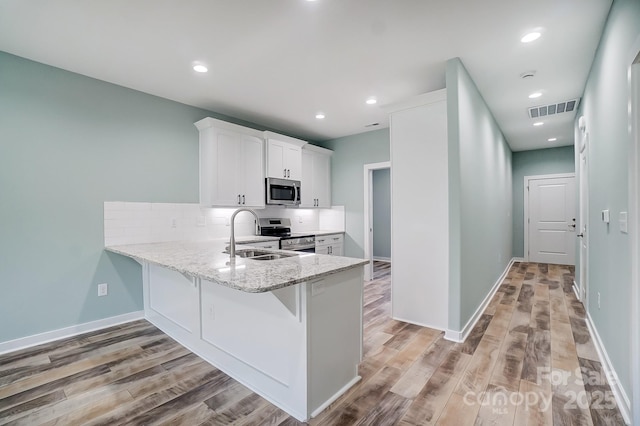 kitchen featuring light hardwood / wood-style flooring, sink, tasteful backsplash, white cabinetry, and stainless steel appliances