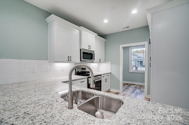 kitchen featuring light stone counters, decorative backsplash, white cabinets, and stainless steel appliances