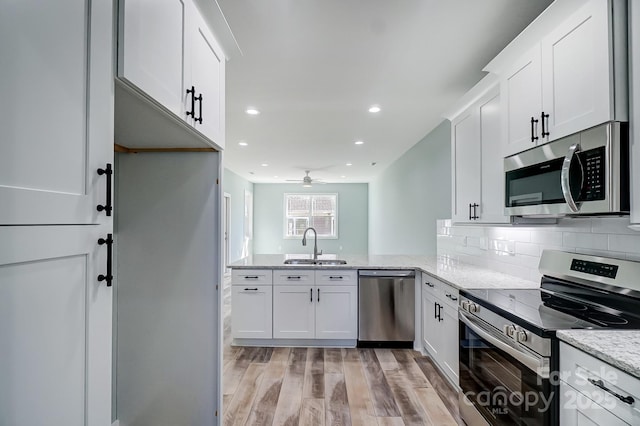 kitchen featuring sink, kitchen peninsula, white cabinets, and appliances with stainless steel finishes