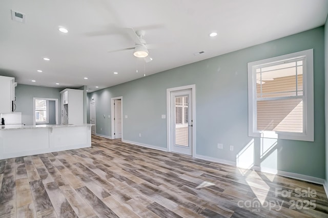 unfurnished living room featuring ceiling fan, sink, and light hardwood / wood-style flooring