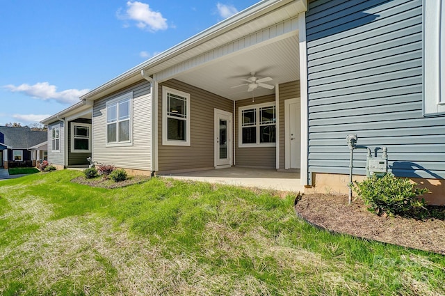 rear view of property featuring ceiling fan, a patio area, and a yard