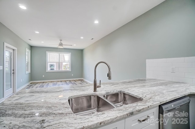 kitchen with light stone countertops, dishwasher, white cabinetry, sink, and backsplash