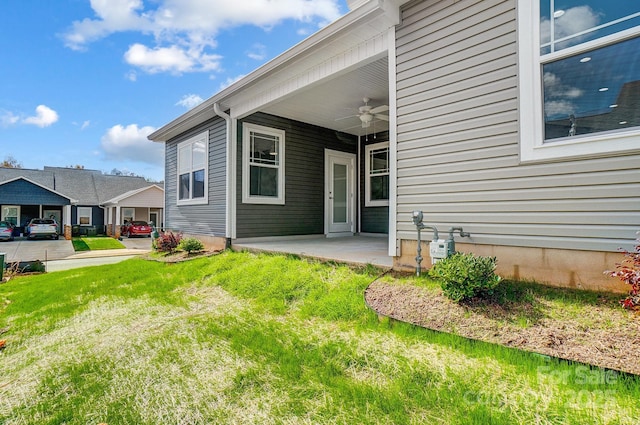 entrance to property with ceiling fan and a yard