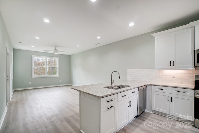 kitchen with kitchen peninsula, dishwasher, sink, white cabinetry, and tasteful backsplash