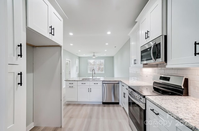 kitchen with sink, backsplash, appliances with stainless steel finishes, and white cabinets