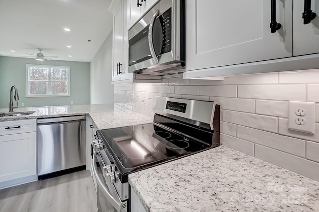 kitchen featuring light stone countertops, sink, white cabinetry, and appliances with stainless steel finishes