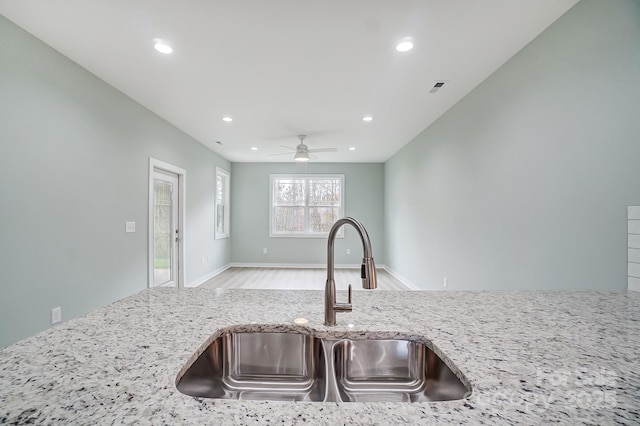 kitchen featuring sink, ceiling fan, light hardwood / wood-style flooring, and light stone countertops