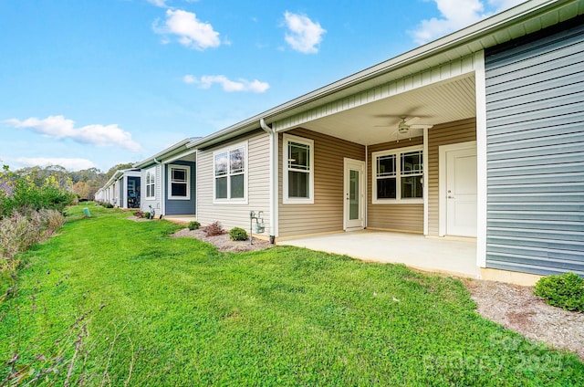 back of property with a yard, a patio, and ceiling fan