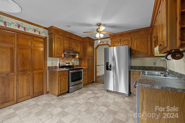 kitchen featuring stainless steel appliances, dark countertops, a sink, and under cabinet range hood