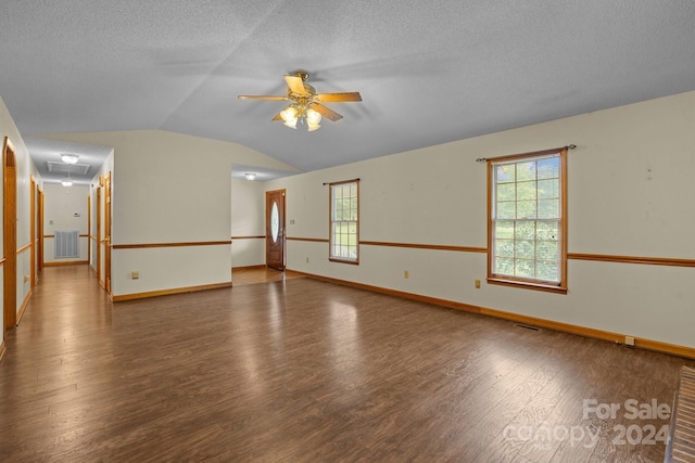 spare room featuring dark wood-style floors, a wealth of natural light, vaulted ceiling, and attic access