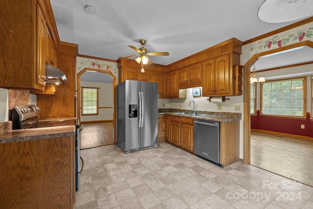 kitchen featuring arched walkways, brown cabinetry, dark countertops, stainless steel appliances, and exhaust hood