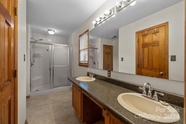 full bathroom featuring visible vents, a sink, a shower stall, and double vanity