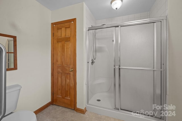 bathroom featuring toilet, a stall shower, and baseboards