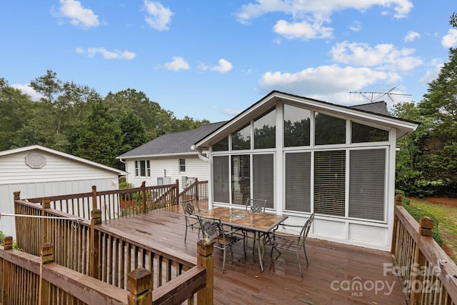 wooden terrace featuring outdoor dining area and a sunroom