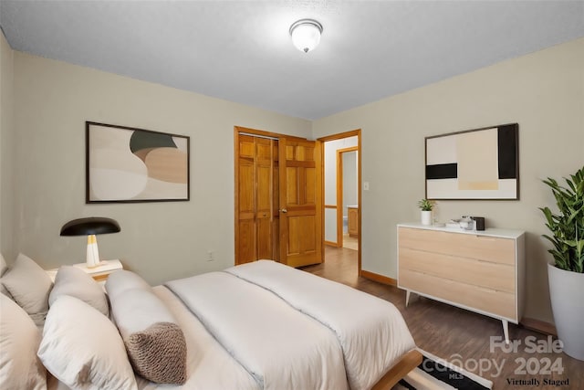 bedroom with dark wood-type flooring, a closet, and baseboards