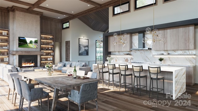 dining room with beam ceiling, an inviting chandelier, a high ceiling, hardwood / wood-style flooring, and a high end fireplace