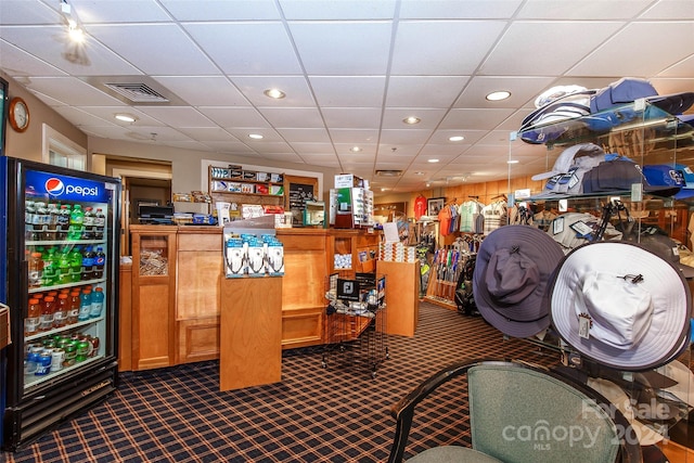 bar with a paneled ceiling and black fridge