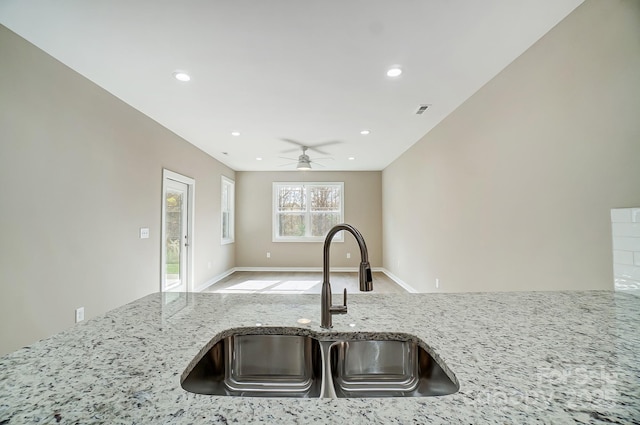 kitchen with sink, ceiling fan, and light stone countertops