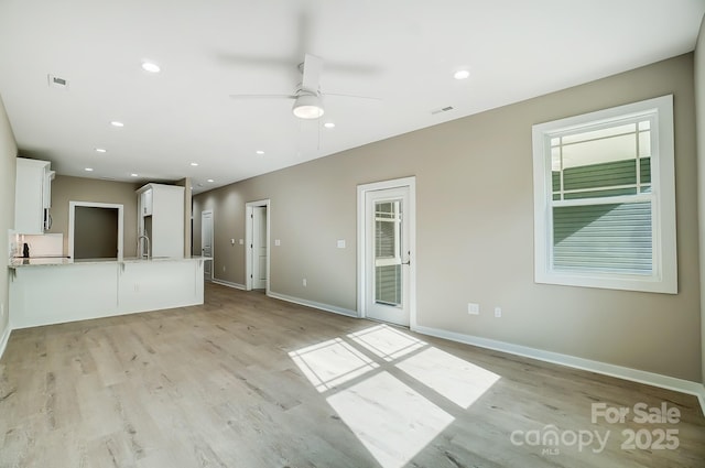 unfurnished living room with sink, ceiling fan, and light hardwood / wood-style floors