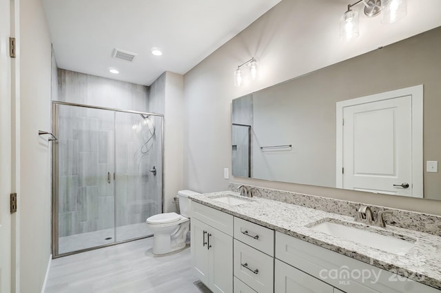 bathroom with hardwood / wood-style floors, toilet, a shower with shower door, and vanity