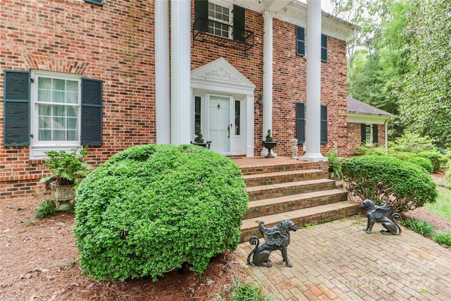 view of exterior entry featuring a patio and brick siding