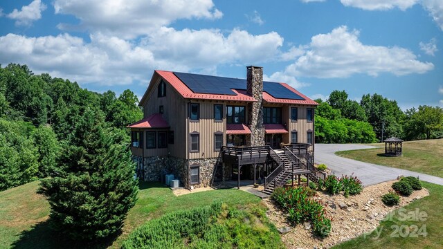 rear view of house with solar panels, a yard, and central air condition unit