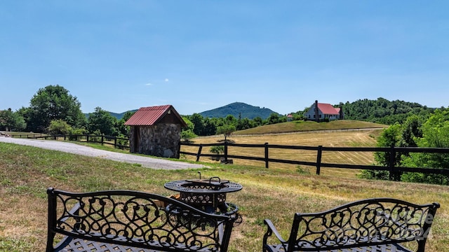 view of yard featuring a storage shed, a mountain view, and a rural view