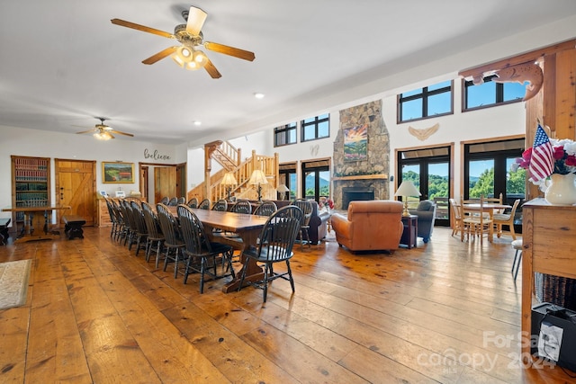 dining space with hardwood / wood-style flooring, a stone fireplace, and ceiling fan