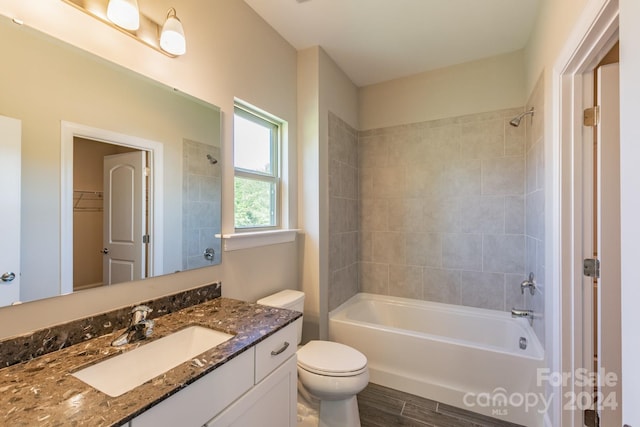 full bathroom featuring vanity, tiled shower / bath, hardwood / wood-style flooring, and toilet