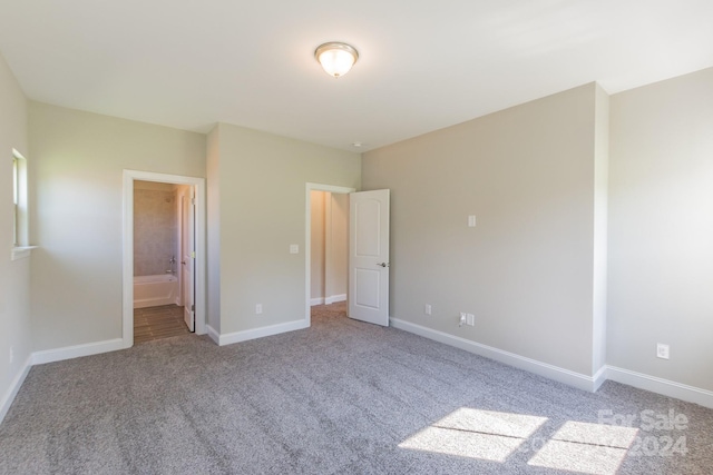 unfurnished bedroom with ensuite bathroom and light colored carpet