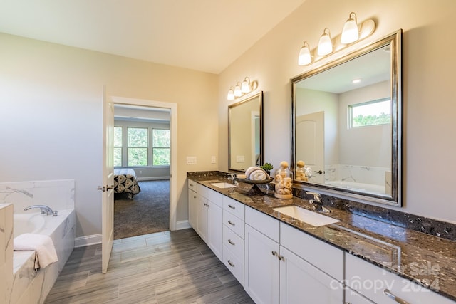 bathroom featuring vanity, a wealth of natural light, and tiled tub