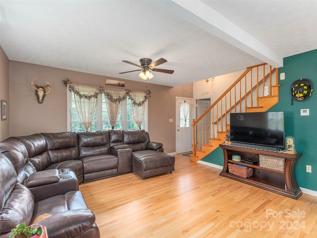 living room featuring beamed ceiling, ceiling fan, and light wood-type flooring