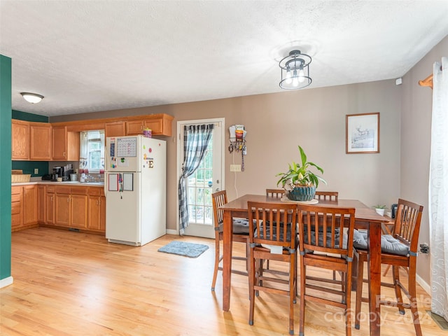 dining room with light hardwood / wood-style flooring, sink, and a textured ceiling