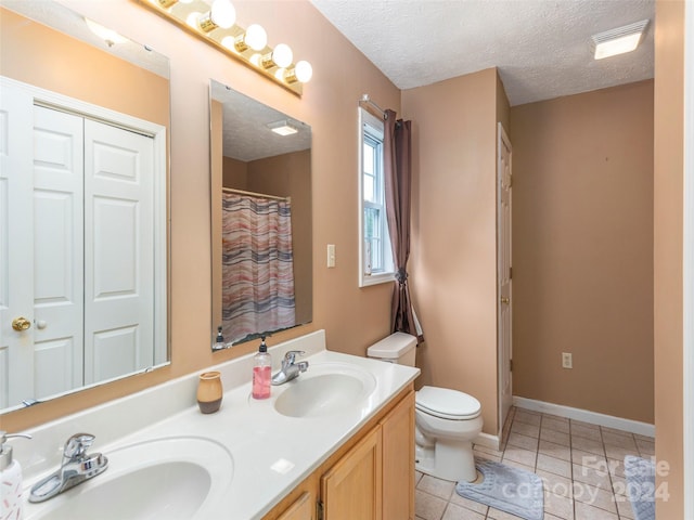 bathroom featuring dual vanity, tile patterned floors, toilet, and a textured ceiling