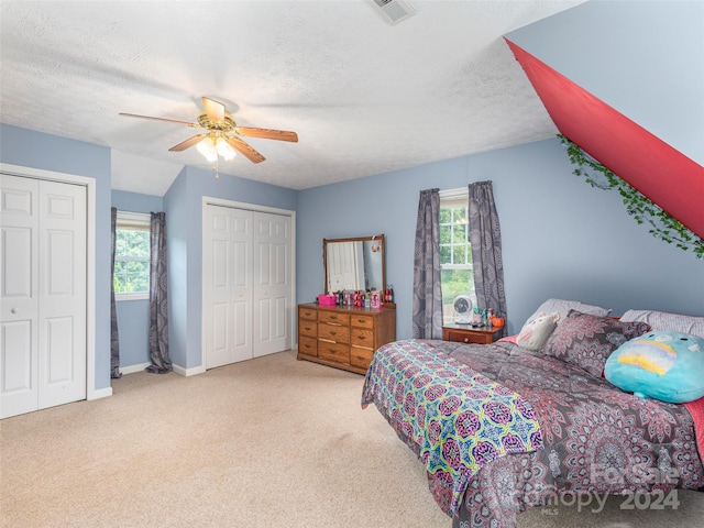 carpeted bedroom featuring multiple windows, a textured ceiling, ceiling fan, and vaulted ceiling