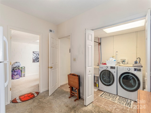 clothes washing area with washer and dryer and light tile patterned floors