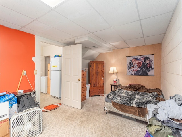 bedroom featuring light carpet, white refrigerator, and a drop ceiling