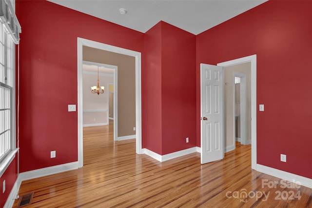 unfurnished bedroom featuring a chandelier and light hardwood / wood-style floors