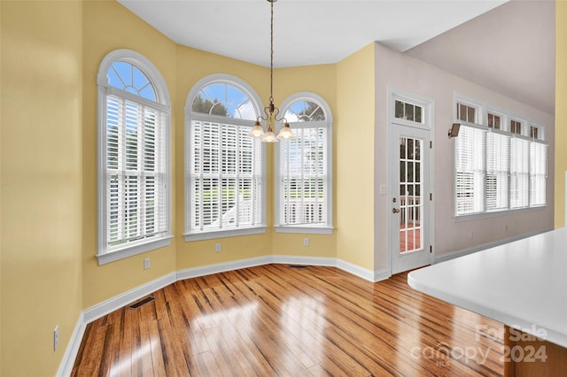 unfurnished dining area featuring a chandelier and hardwood / wood-style floors