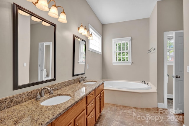 bathroom with dual vanity, plenty of natural light, a bathtub, and tile patterned floors