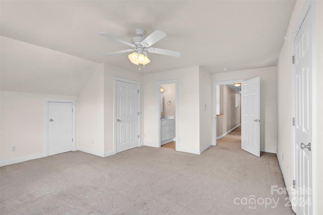 unfurnished bedroom featuring light colored carpet, connected bathroom, vaulted ceiling, and ceiling fan