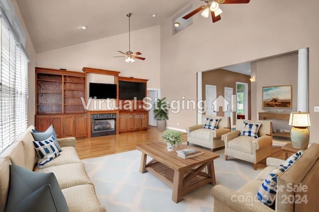 living room featuring a fireplace, ceiling fan, high vaulted ceiling, and light hardwood / wood-style floors